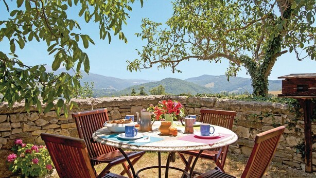 A round table with chairs, a stone wall, and a view of mountains. - Gorgeous home in Pieve S. Stefano AR (Pieve S. Stefano AR)