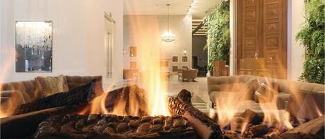 Ein gemütliches Wohnzimmer mit Kamin, zwei Sofas und einem Essbereich im Hintergrund.
