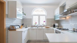 Een moderne keuken met witte kastjes, een centraal eiland, een raam met uitzicht en een fornuis.