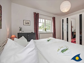 Una habitación de hotel con una cama, un escritorio, una lámpara, una ventana con cortinas y un armario.