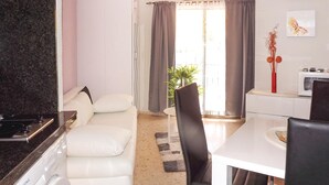 A modern living room with a sofa, a dining table, and a kitchen area with a washing machine. - Nice apartment in Denia with swimming pool (Denia)