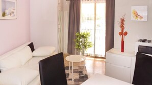 A modern living room with a white sofa, a small round table, and a white cabinet. - Nice apartment in Denia with swimming pool (Denia)
