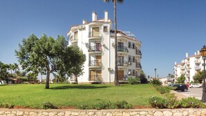 A multi-story residential building with balconies, surrounded by well-maintained lawns and palm trees. - Nice apartment in Denia with swimming pool (Denia)