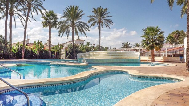 A swimming pool with multiple sections and palm trees in the background. - Nice apartment in Denia with swimming pool (Denia)