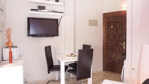 A small, compact room with a white desk, two black chairs, a television mounted on the wall, and a wooden door. - Nice apartment in Denia with swimming pool (Denia)