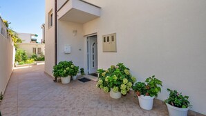 A narrow, tiled corridor with potted plants and a door leading to a building. - 2 bedroom beach front apartment in Makarska (Makarska)