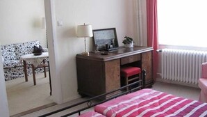 A hotel room with a bed, a desk, a chair, and a radiator. - Apartment Hannah (Neubrandenburg)