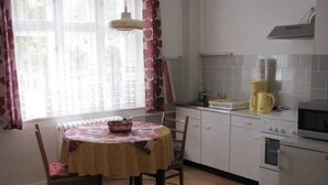 A kitchen with a round table, chairs, a radiator, a stove, and a microwave. - Apartment Hannah (Neubrandenburg)