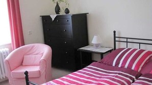 A bedroom with a bed, a chair, a dresser, and a nightstand. - Apartment Hannah (Neubrandenburg)
