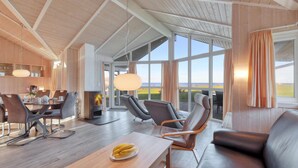 A spacious living room with a large window offering a view of the outdoors. There is a dining area with a table and chairs, and a seating area with sofas and chairs. - Amazing home in Schönhagen with sauna (Schönhagen)