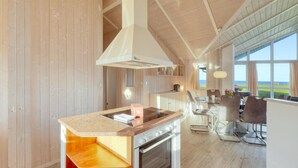 A modern kitchen with a central island, built-in oven, and large windows offering a view of the outdoors. - Amazing home in Schönhagen with sauna (Schönhagen)