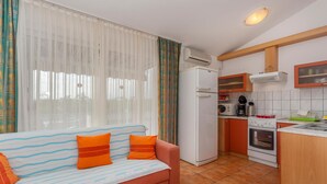 A compact living space with a sofa, a kitchenette, and a window with sheer curtains. - 2 bedroom cozy apartment in Punat (Punat)