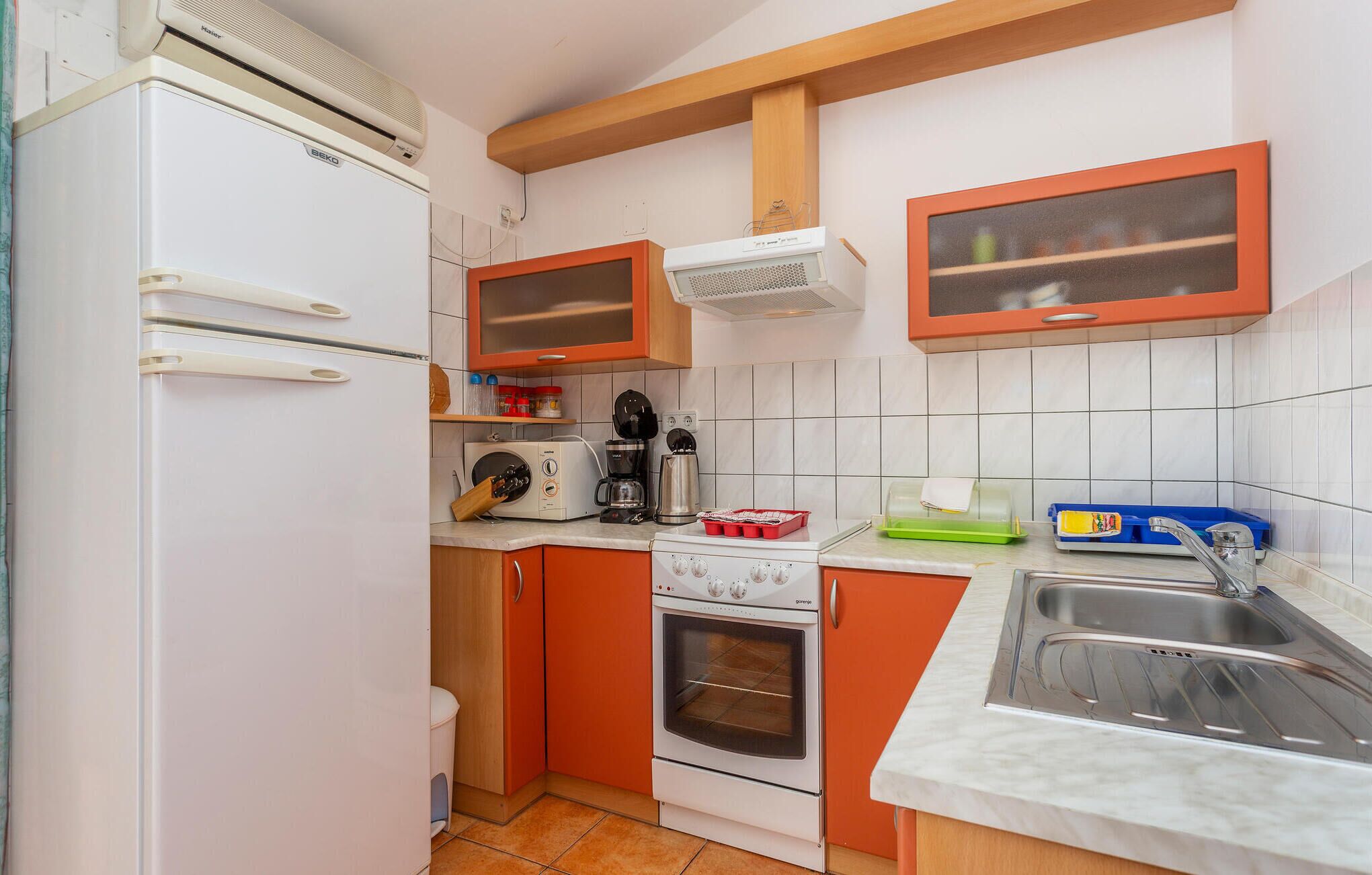 A compact kitchen with a refrigerator, oven, microwave, and a sink.