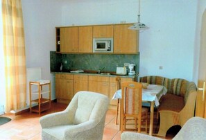A compact living space with a kitchenette, a dining area, and a seating arrangement. - Fewo - Rügen apartment 103 (Wiek)