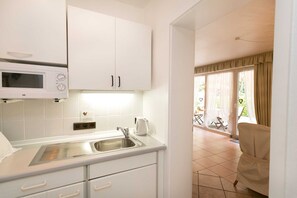 A modern kitchen with white cabinets, a built-in microwave, and a stainless steel sink.