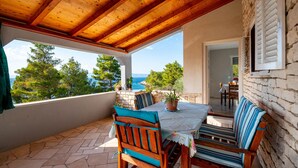 A covered outdoor dining area with stone flooring, wooden furniture, and a view of the sea. - Gorgeous home in Tankaraca with WiFi (Tankaraca)