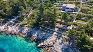 A coastal property with stone pathways, a house with a tiled roof, and surrounding greenery. - Gorgeous home in Tankaraca with WiFi (Tankaraca)