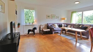A living room with a wooden floor, a sofa, a rocking horse, a table, and a television. - 3 bedroom gorgeous home in Yngsjö (Yngsjö)