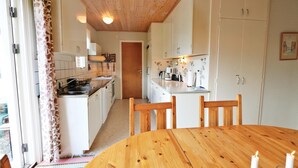 A kitchen with white cabinets, a wooden ceiling, and a dining area with a round wooden table and chairs. - 3 bedroom gorgeous home in Yngsjö (Yngsjö)
