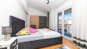 Un dormitorio moderno con cama, lámpara de noche, cabecera de madera y vistas al exterior.