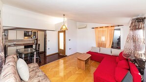 Un espacio habitable compacto con kitchenette, comedor y sofá rojo.