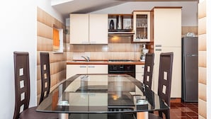 Una cocina compacta con una mesa de comedor de vidrio, sillas oscuras y un horno empotrado.