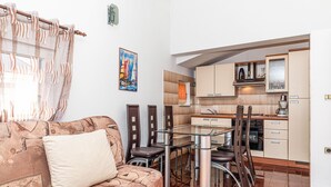 Un espacio habitable compacto con sofá, una mesa de comedor y una zona de cocina.