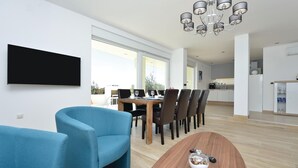 Una sala de estar moderna con comedor, cocina y un amplio ventanal que proporciona luz natural.