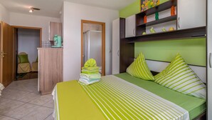 Un dormitorio con cama, armario, escritorio y silla.