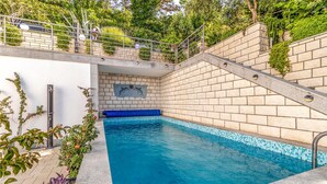 Una piscina con borde de azulejos, un banco azul y una pared de piedra.