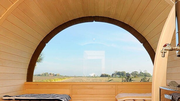 Una sauna con bancos de madera, un tapete negro y un cubo de madera.