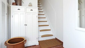 Una escalera con paredes blancas y piso marrón, que conduce a una habitación con una puerta blanca.