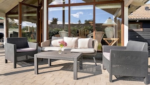 An outdoor patio area with wicker furniture, including a sofa and chairs, and a coffee table. - Stunning home in Væggerløse with sauna (Væggerløse)