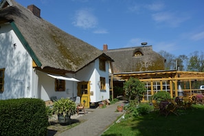 A traditional building with a thatched roof, a covered outdoor seating area, and a pathway leading to the entrance. - 3 - "Up'n Hoff", Germany (Middelhagen)