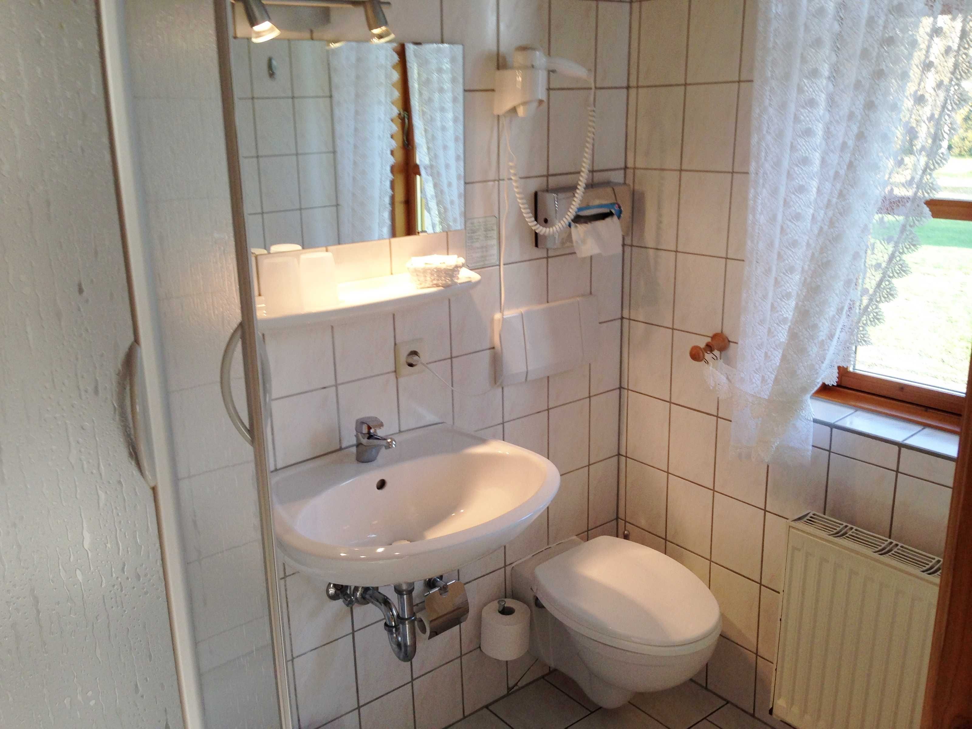 Pieni kylpyhuone, jossa on pesuallas, wc ja peili.
