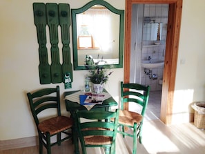 A dining area with a table, chairs, a mirror, and a view into the kitchen. - 3 - "Up'n Hoff", Germany (Middelhagen)