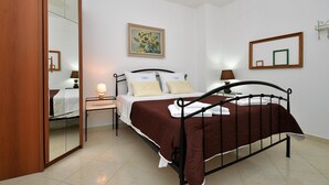 Un dormitorio con cama, mesita de noche, espejo y un cuadro en la pared.