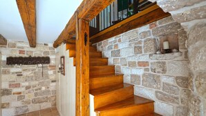 Una escalera de madera con paredes de piedra y barandilla de metal.