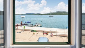 Un puerto deportivo con barcos amarrados, un niño jugando con un coche de juguete y una vista despejada del agua y colinas distantes.