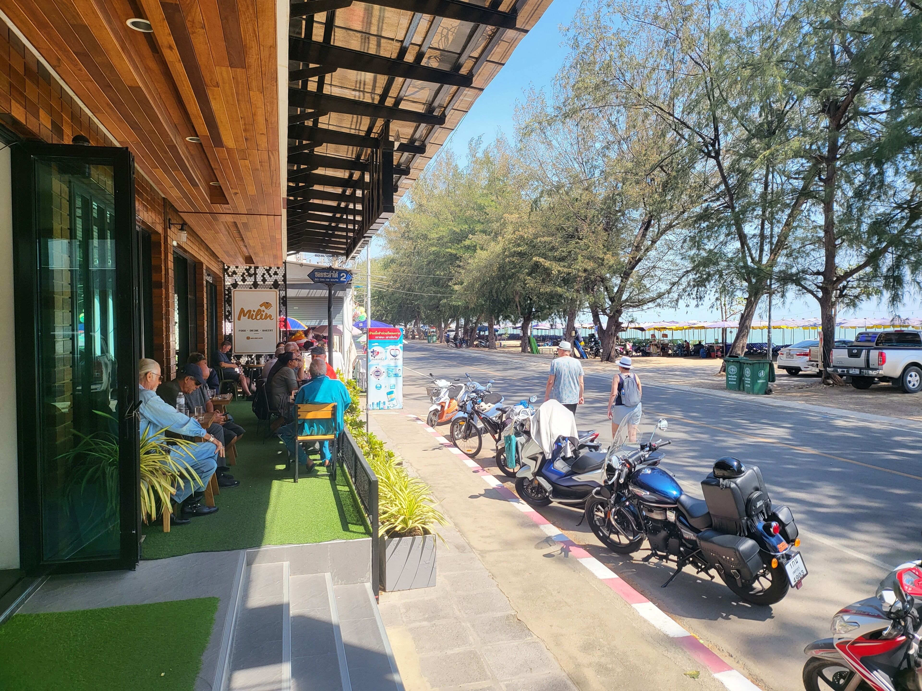 A restaurant with outdoor seating, a covered area, and a row of parked motorcycles.