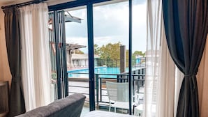 A hotel room with a bed, a sofa, a view of a swimming pool, and a balcony with a chair. - Irin Beach Cha - am (Cha-am)