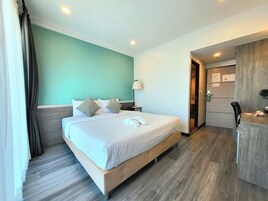 Habitación de hotel con cama, mesita de noche, lámpara y puerta que da a un baño.