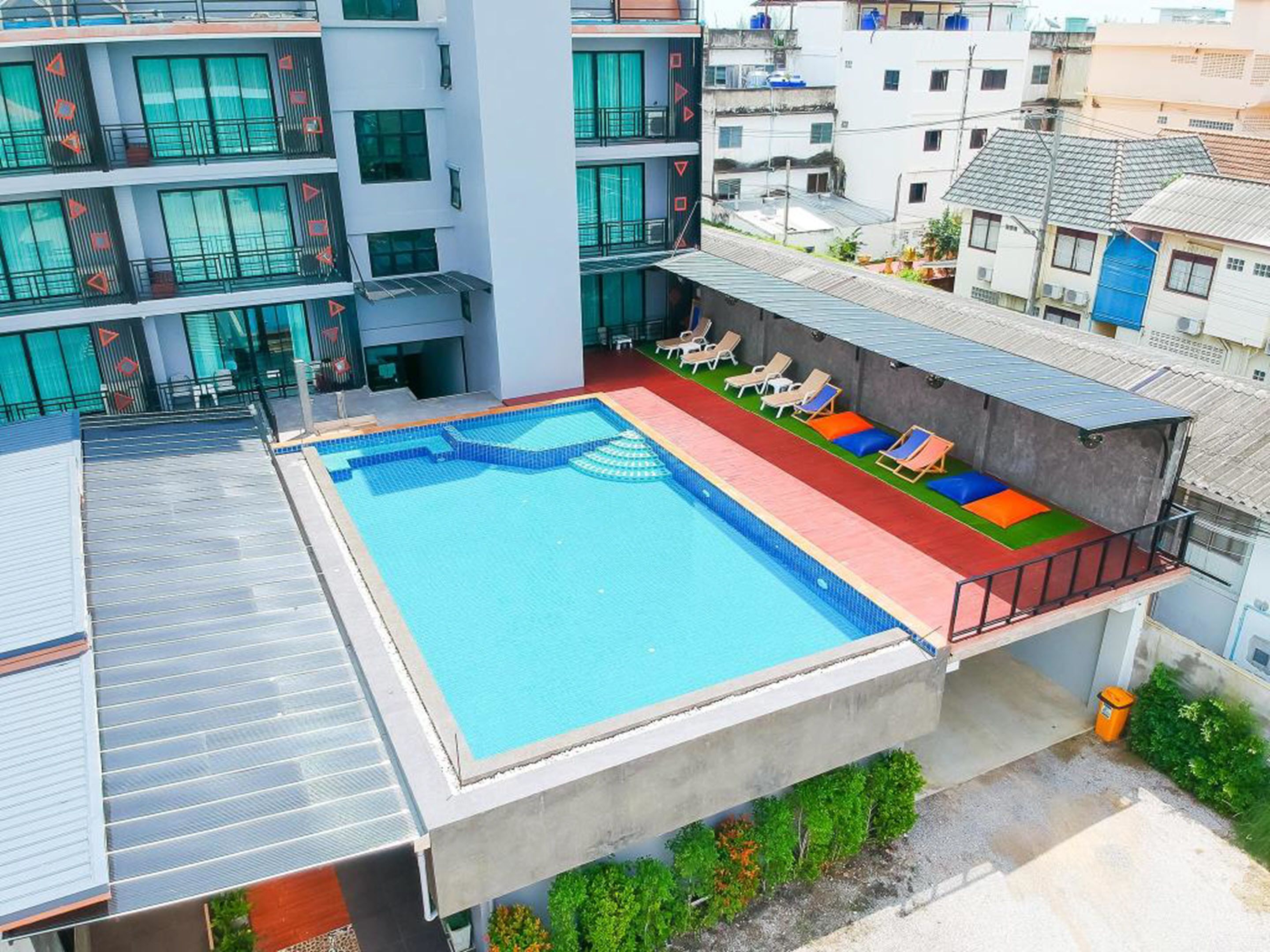 A rooftop swimming pool with a clear blue water feature, surrounded by lounge chairs and a small deck area.