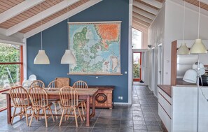 Un coin repas avec une table et des chaises en bois, une grande carte accrochée au mur et des luminaires suspendus.