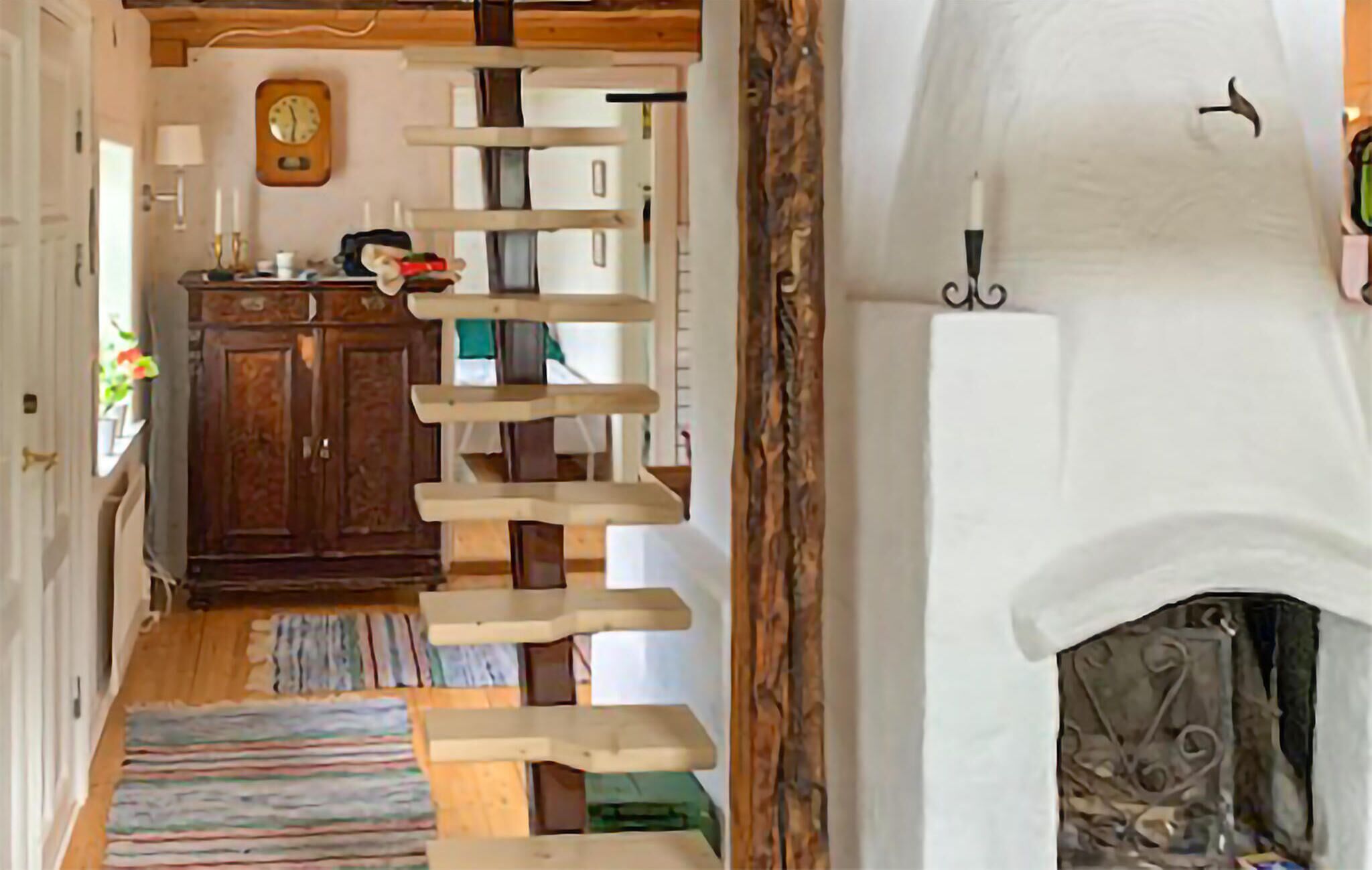 Un escalier au design original, un meuble en bois, une horloge et une cheminée.