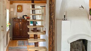 Un escalier au design original, un meuble en bois, une horloge et une cheminée.