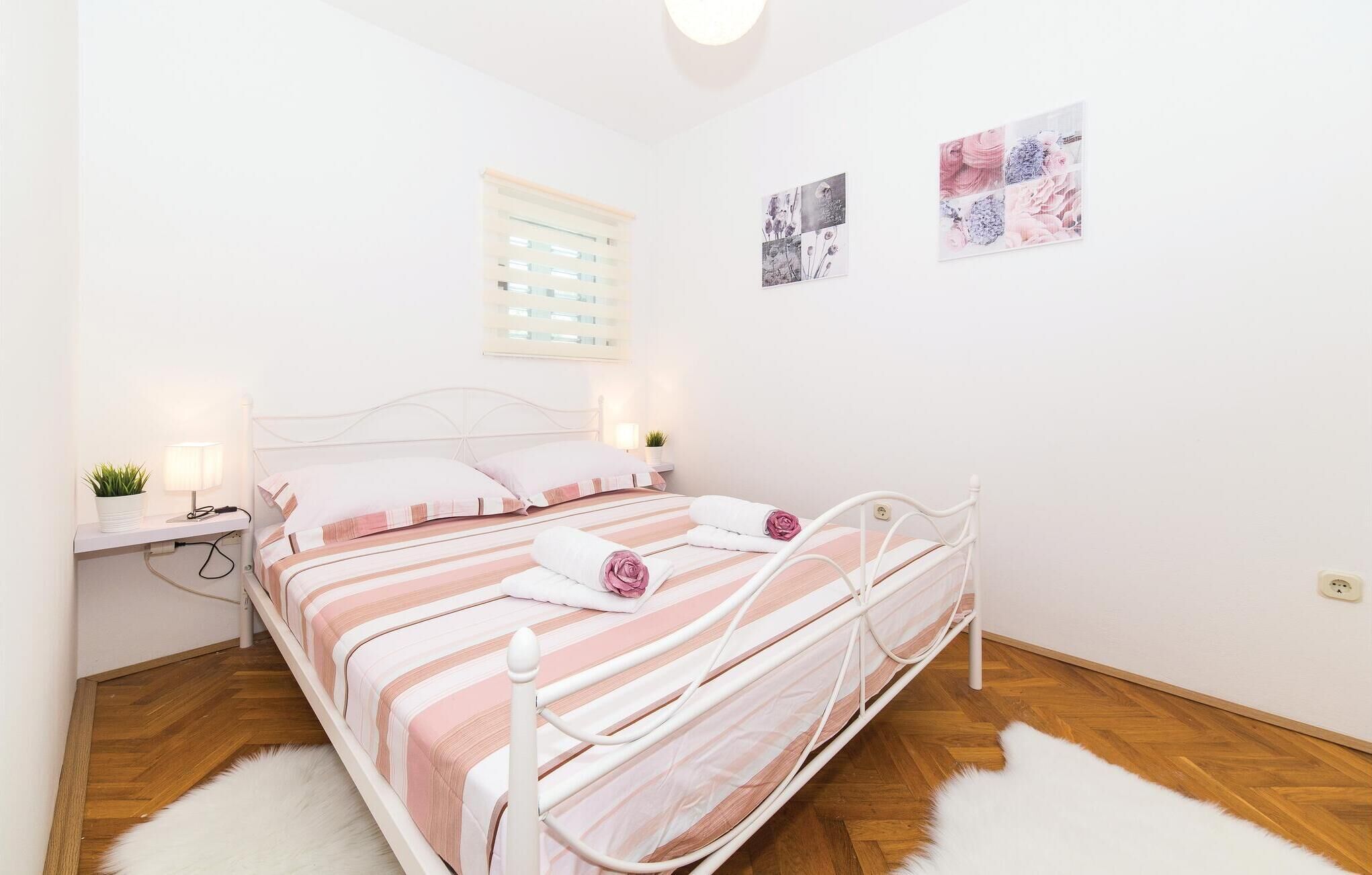 A neatly arranged bedroom with a bed, bedside tables, a wall-mounted light, and a window with blinds.