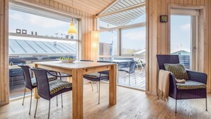 Un interior de madera con comedor, ventanas amplias y vista al techo.