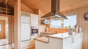 Una cocina moderna con paredes de madera, una isla central, horno empotrado, microondas y una ventana con vistas.