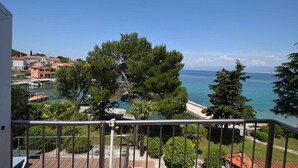A balcony with a view of a coastal town, a body of water, and boats. - Holiday apartment mit Balkon und Meerblick (Malinska)